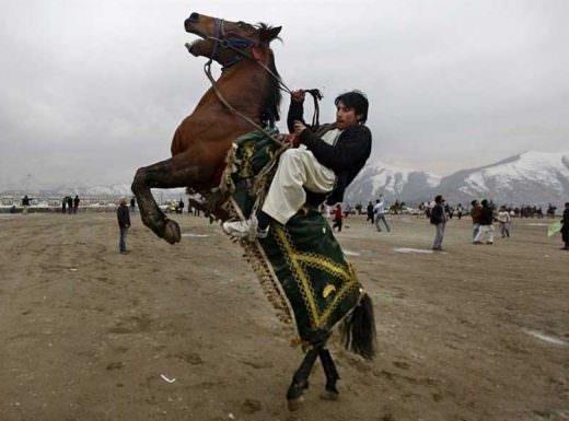 A middle eastern man rides his horse into a rear while pulling violently on the reins.